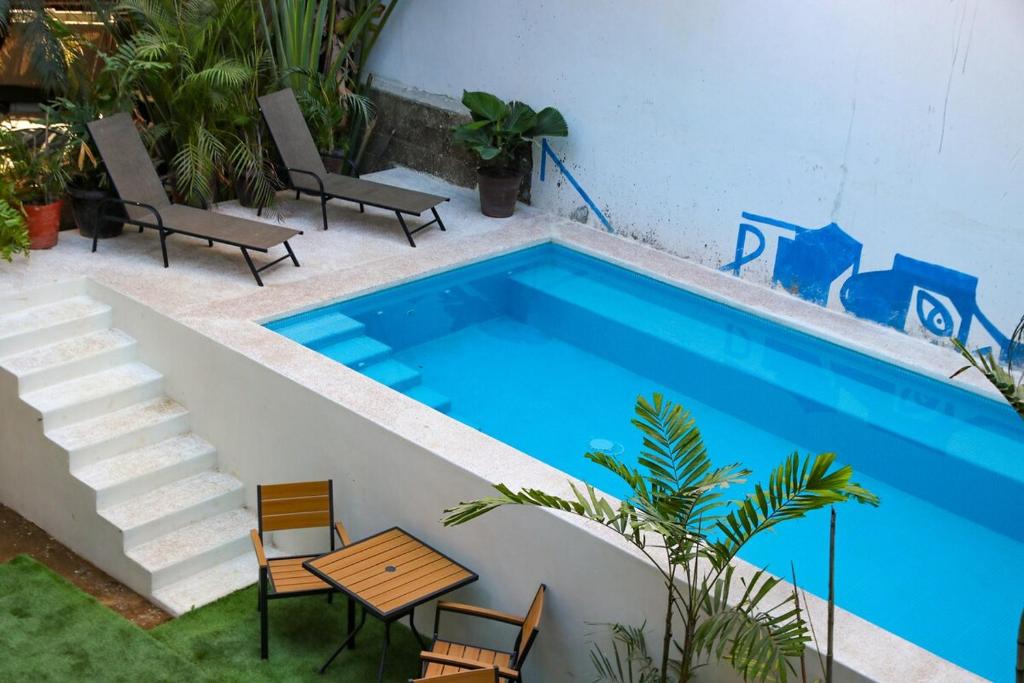 a swimming pool with chairs and a table next to a building at Patio Canarias Chacala Suites Pet-Friendly in Chacala