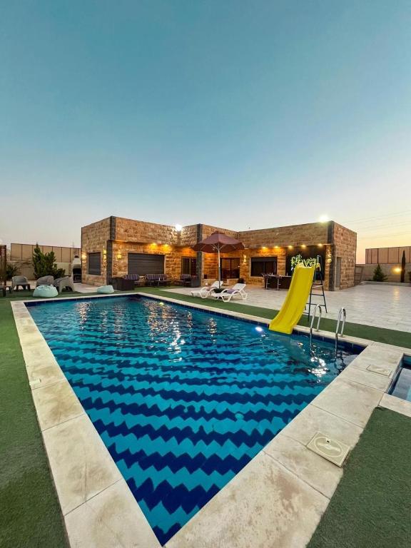 a swimming pool with a slide in front of a building at شاليهات الشهد والحلا in Amman