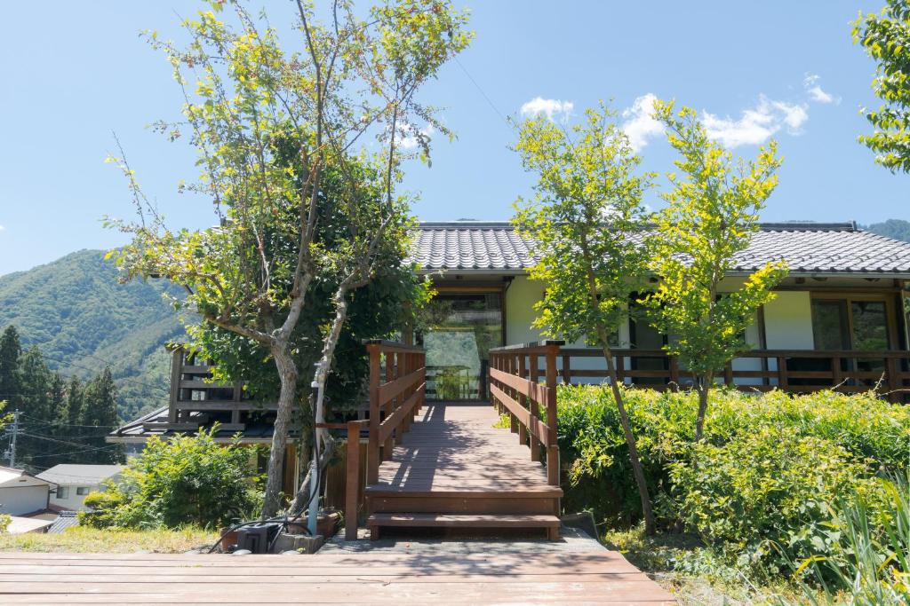 a wooden walkway leading to a house with trees at Nakasendo Shiki - Private Garden Villa in Nagiso