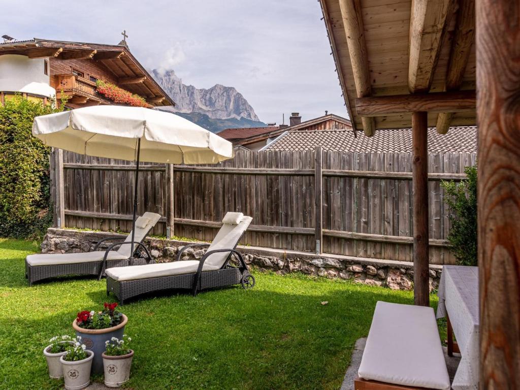 a yard with two chairs and an umbrella at Dorf30 in Going am Wilden Kaiser