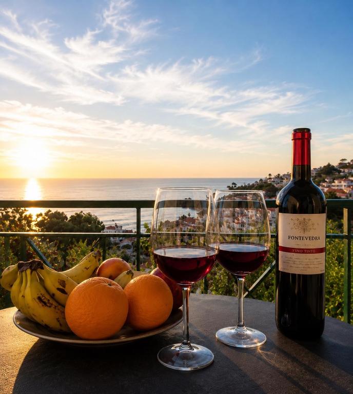 a plate of fruit and two glasses of wine on a table at Ocean Breeze in Caniço
