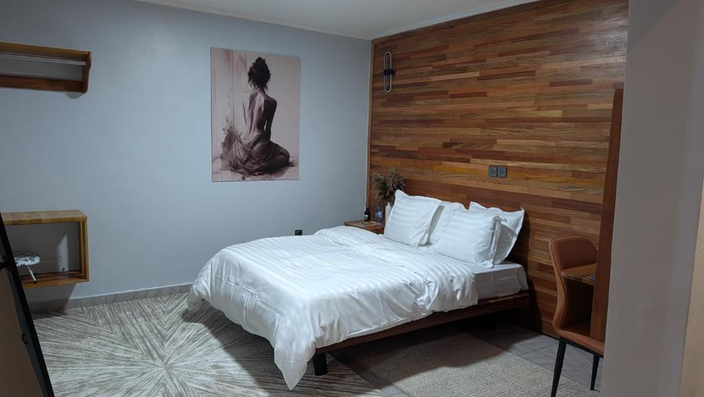 a bedroom with a bed with a wooden wall at Le Cocon de Jade - Nylon Bastos in Yaoundé