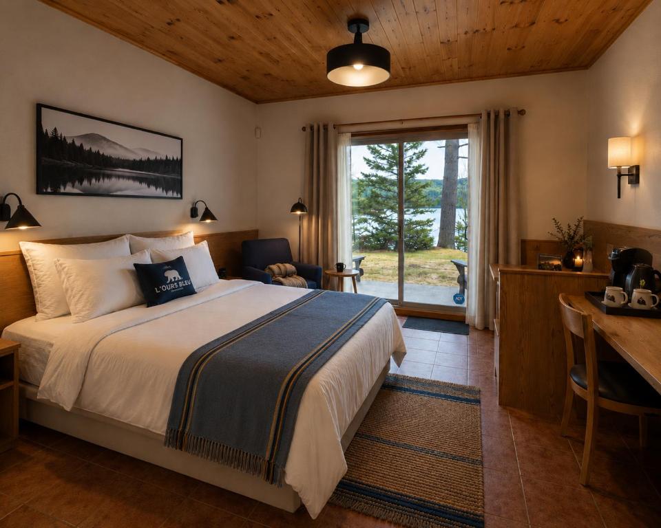 ein Schlafzimmer mit Bett, Schreibtisch und Fenster in der Unterkunft L'Ours Bleu in Lac-Saguay