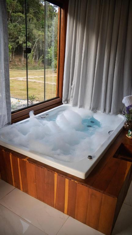 a jacuzzi tub in a room with a window at Chalés Florenzza in Santa Teresa