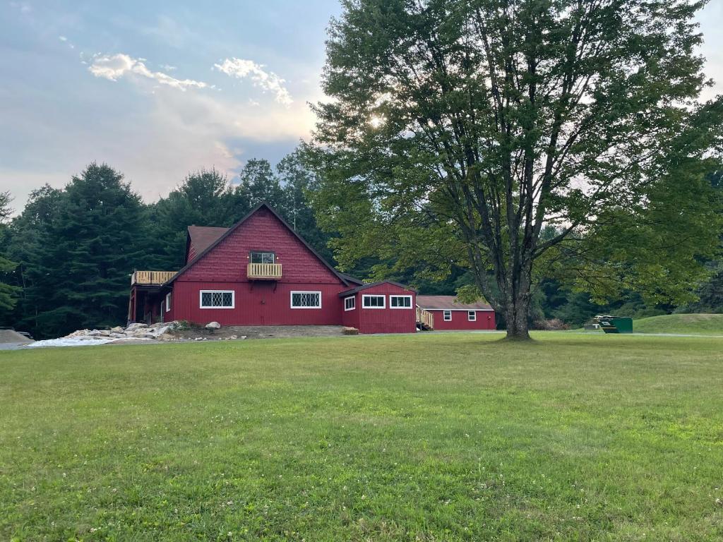 a red barn with a tree in a field at Sweet Forest Breeze, A Cook Forest Inn in Marienville