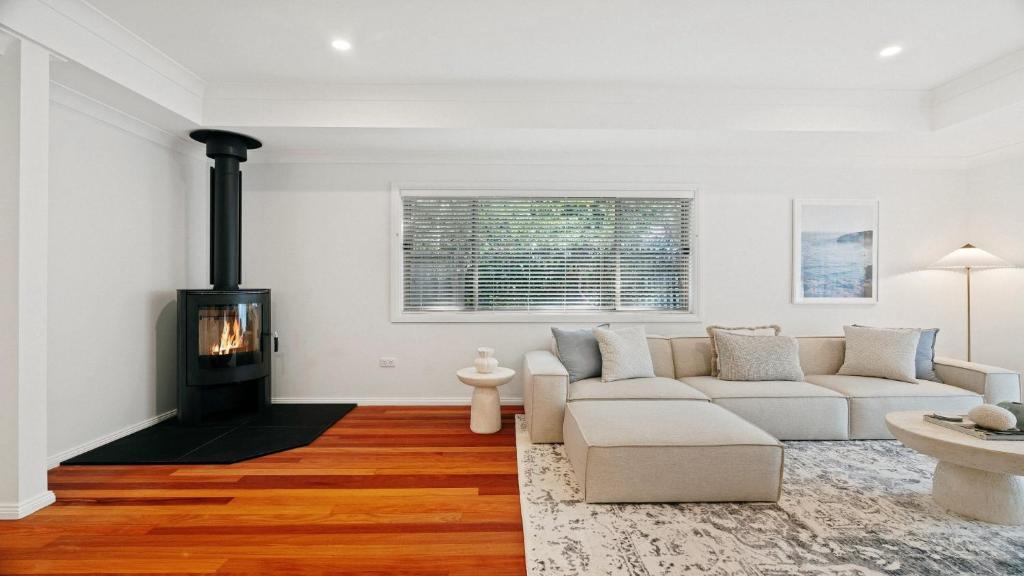 a living room with a couch and a fireplace at Gemburra By Holidayco in Pearl Beach