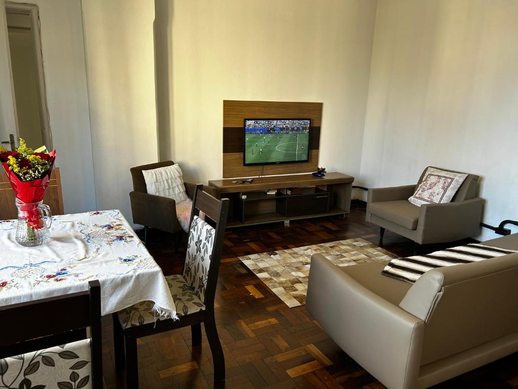 a living room with a television and a table and chairs at Confortavel Apartamento na Rua das Flores in Curitiba