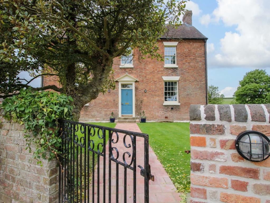 a brick house with a blue door and a tree at Highfields Farm in Church Stretton