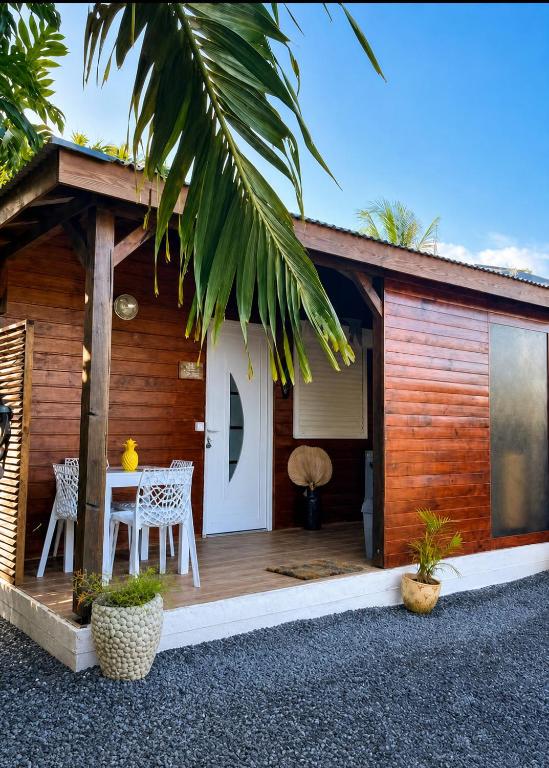 a house with a wooden porch with a table and chairs at Le cocon de Moreau - Spa extérieur in Goyave