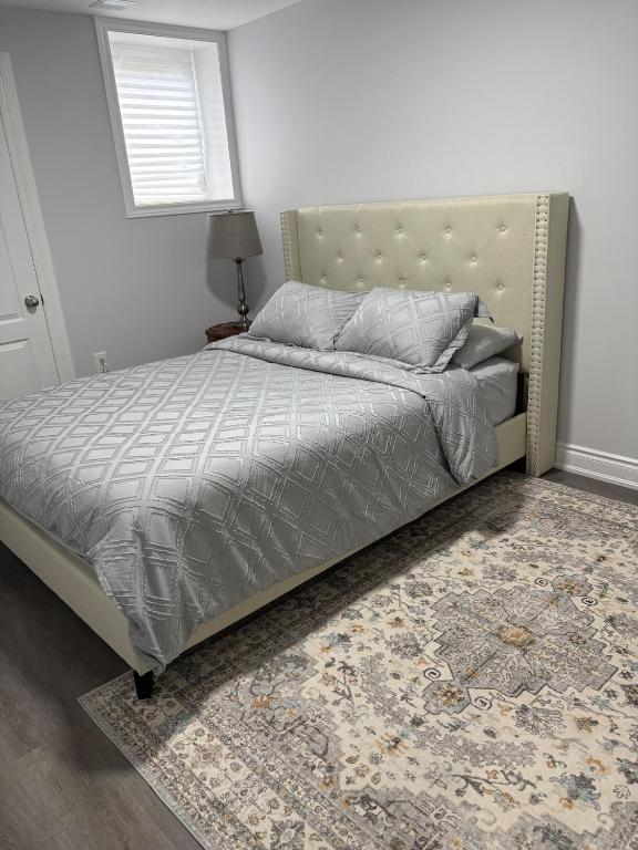 a bedroom with a bed with a headboard and a rug at The Basement apartment in Milton