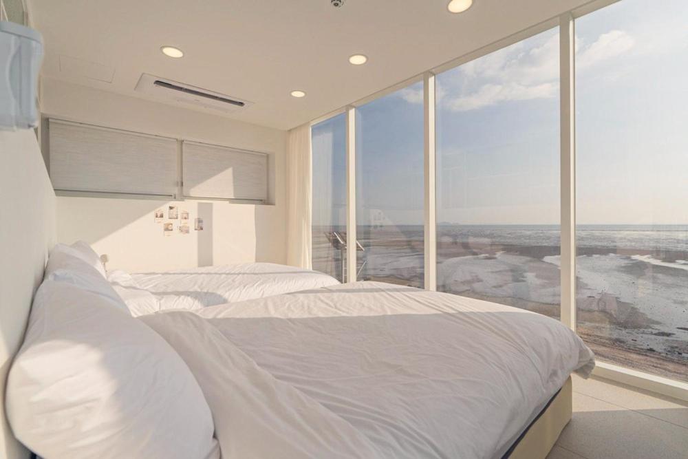 a bedroom with two beds and a large window at Seesun Art Studio Villa in Ansan