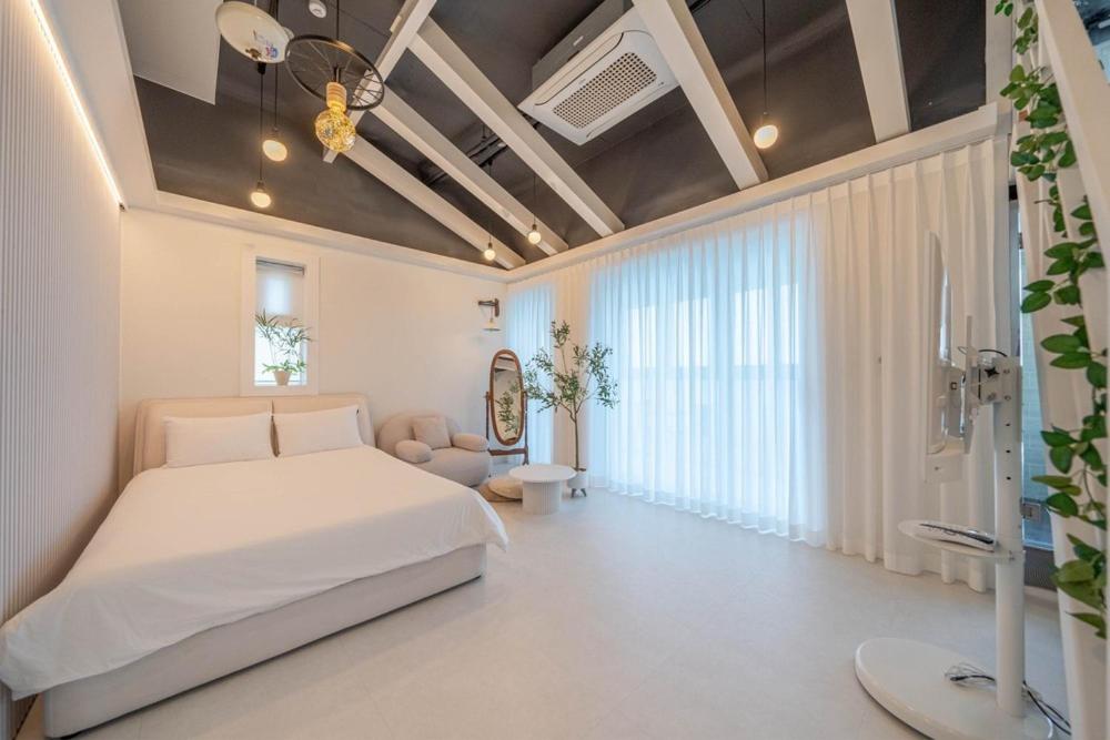 a bedroom with a white bed and a large window at Samcheok Pureun Bada Pension in Samcheok