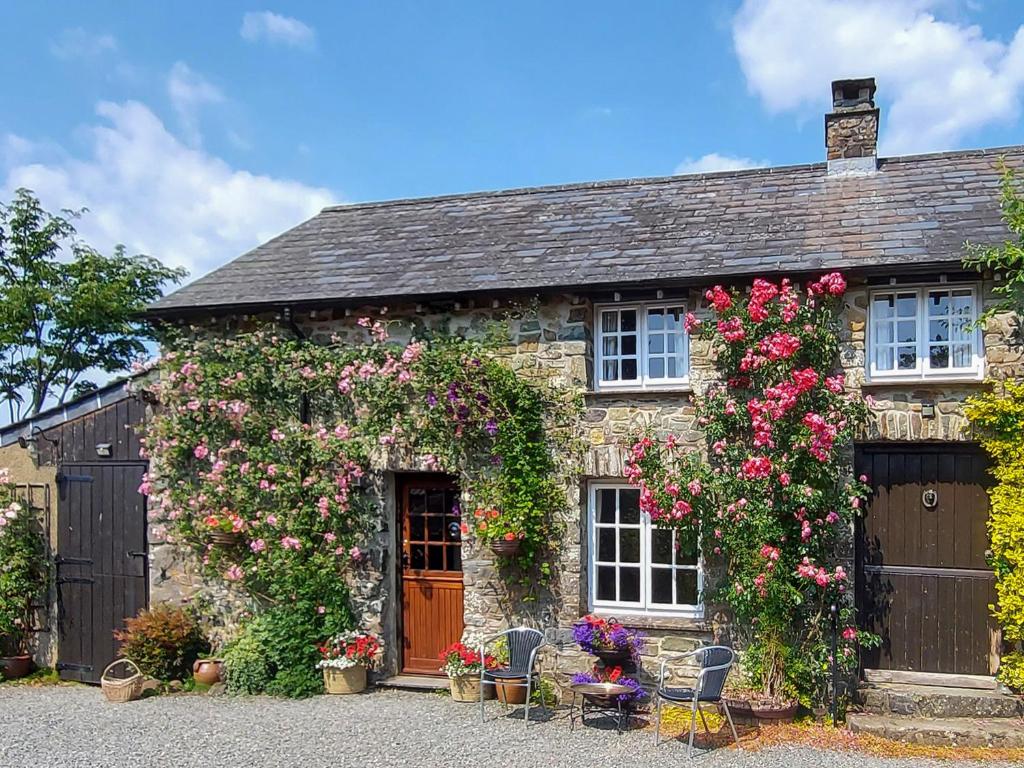 an old stone house with flowers on it at Little Forda in Chillaton