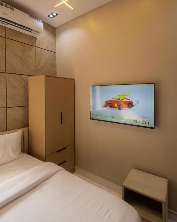a bedroom with a bed and a tv on the wall at Tiny Studio Apartment with Pool and gym in Lekki