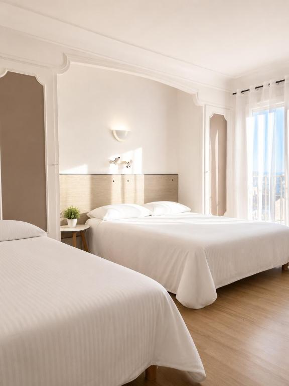 a white bedroom with two beds and a window at Hôtel le Canetois in Canet-en-Roussillon