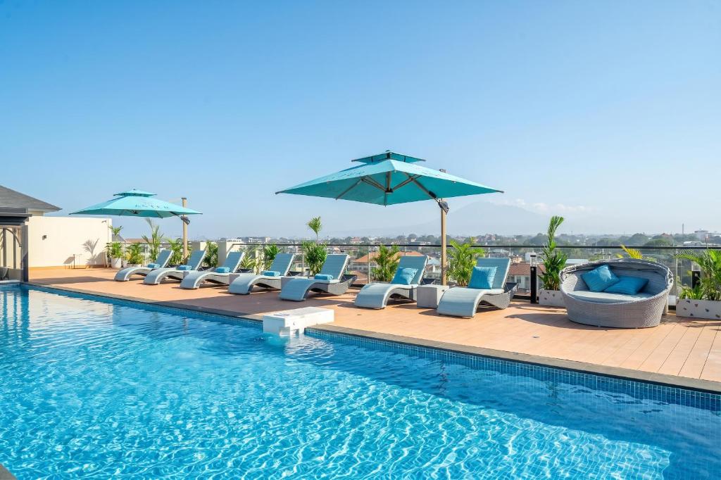 a swimming pool with lounge chairs and umbrellas at Aster Apartments - Stylish Loft with Rooftop Pool & Sauna in Canggu