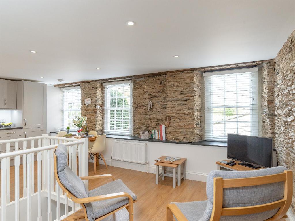 a kitchen and living room with two chairs and a tv at Dayan Cottage in Fowey