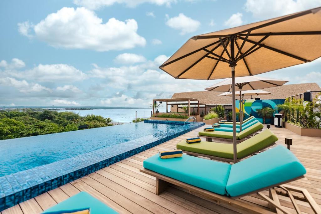 a pool with lounge chairs and an umbrella at MAMAKA Bali in Kuta