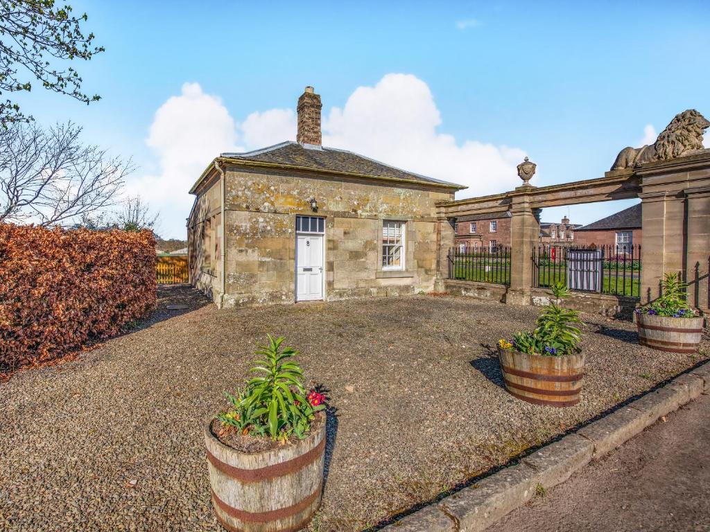 an old stone house with potted plants in front of it at South Lodge - Uk48318 in Berwick-Upon-Tweed