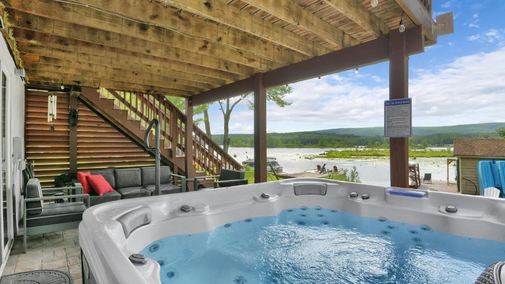 a hot tub on a patio with a view of the water at Waterfront, Hot Tub, Dock Kayaks, Movie Game Room in Lake Ariel