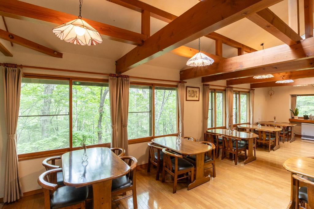 a dining room with tables and chairs and windows at Ikiru Lodge in Yamanouchi