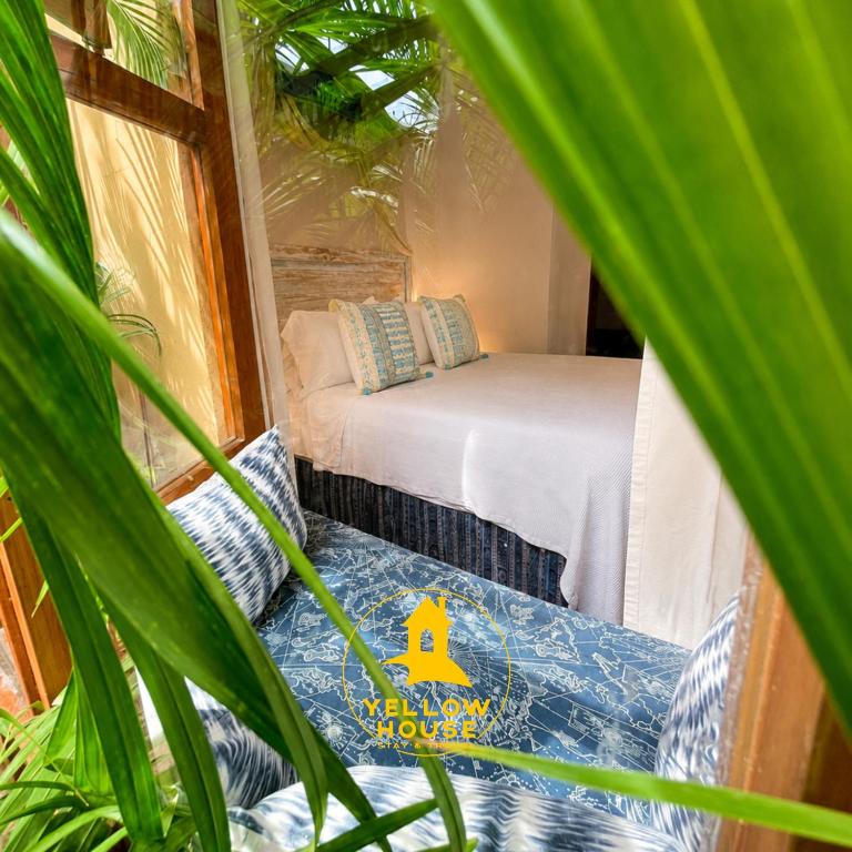 a small room with a bed and some plants at Yellow House Hostel B&B in Antigua Guatemala