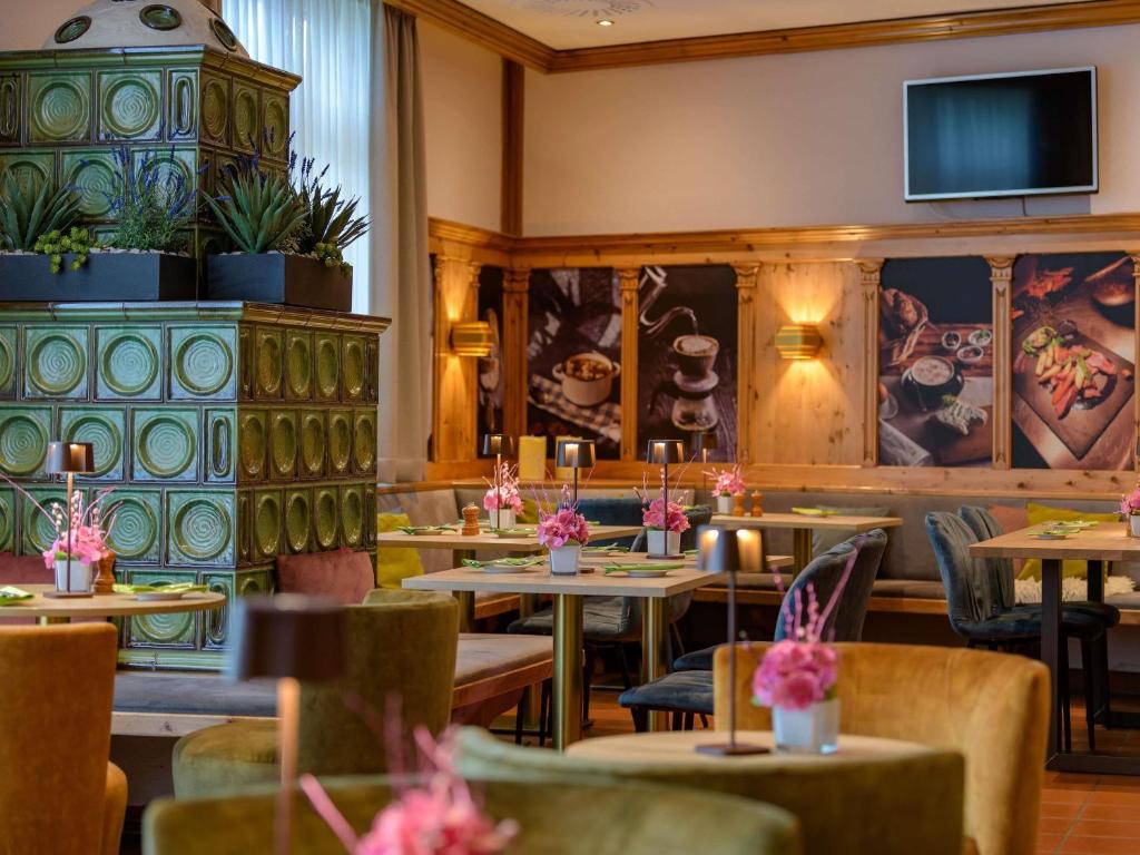 a restaurant with tables and chairs and a tv at Mercure Hotel Stuttgart Airport Messe in Stuttgart