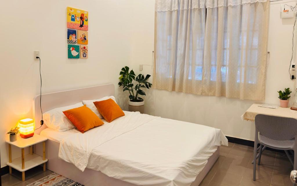 a bedroom with a bed with two orange pillows at Ni Nớ Home in Hue