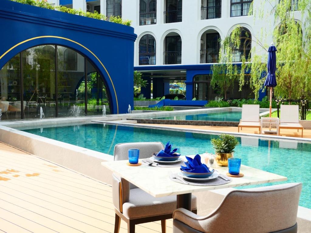 a table and chairs next to a swimming pool at Above Element Bangtao Phuket by Arthouse Collection in Laguna Phuket