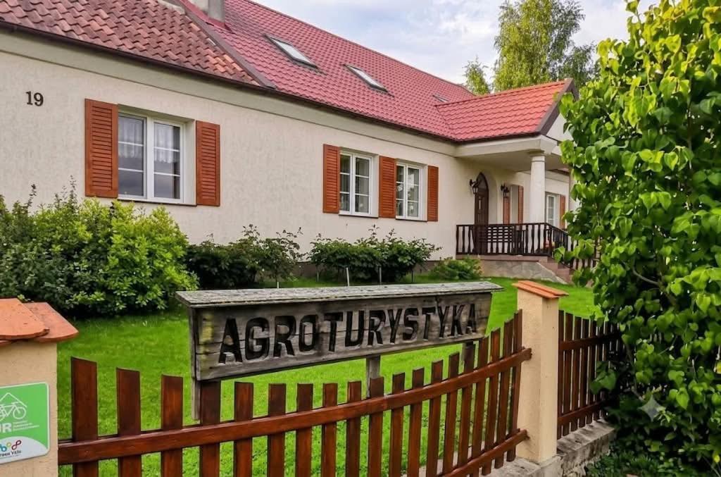 a house with a sign on a fence at Agroturystyka Pod Czaplami in Pieniężno