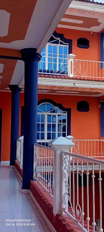 an orange building with blue windows and a balcony at Hostel New Brothers in Panajachel