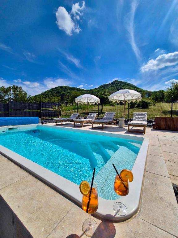 a swimming pool with two wine glasses in front of it at Gyémánt Vendégház in Doba