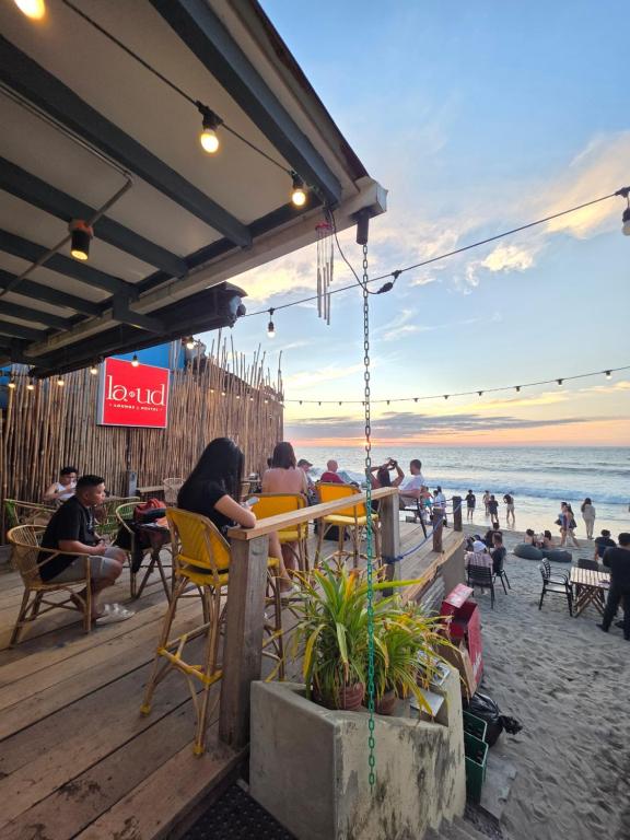a group of people sitting at a bar on the beach at La Ud Lounge and Hostel in San Juan