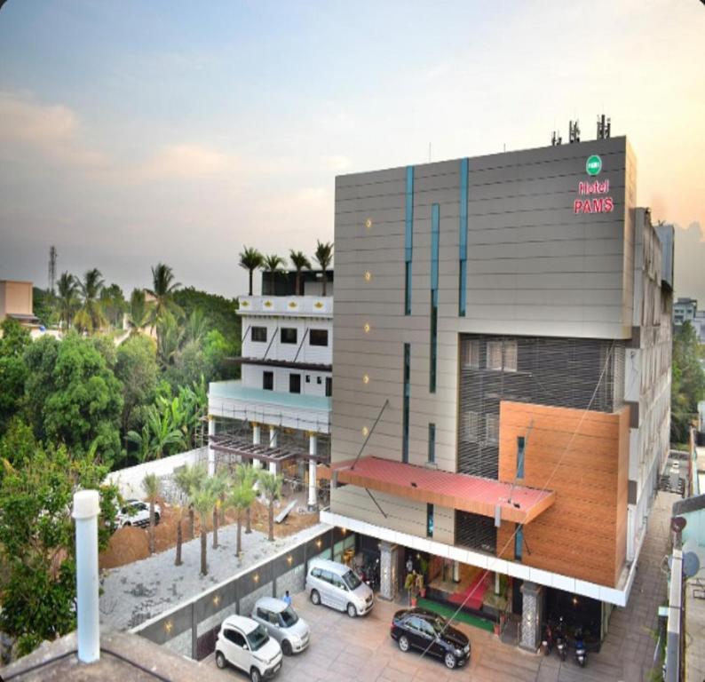 a building with a parking lot in front of it at Hotel PAMS in Mayiladuthurai