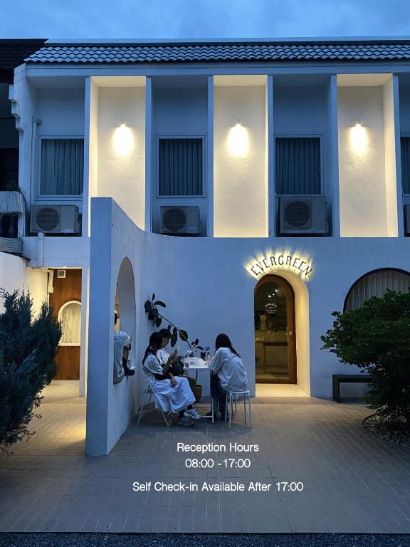 a group of people sitting at a table outside of a building at Evergreen Cafe and Hotel in Chiang Mai