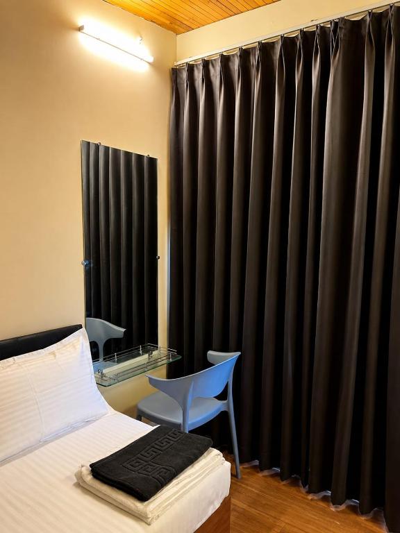 a bedroom with black curtains and a bed and a chair at Fargade Elite Club in Sangamner