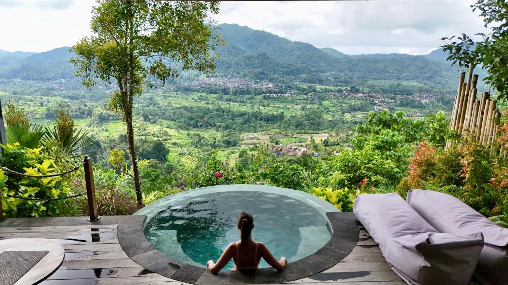 a woman sitting in a glass bowl in a pool at Villa Damai Rohani Private Pool Villas with Valley Views Adults Only in Sidemen