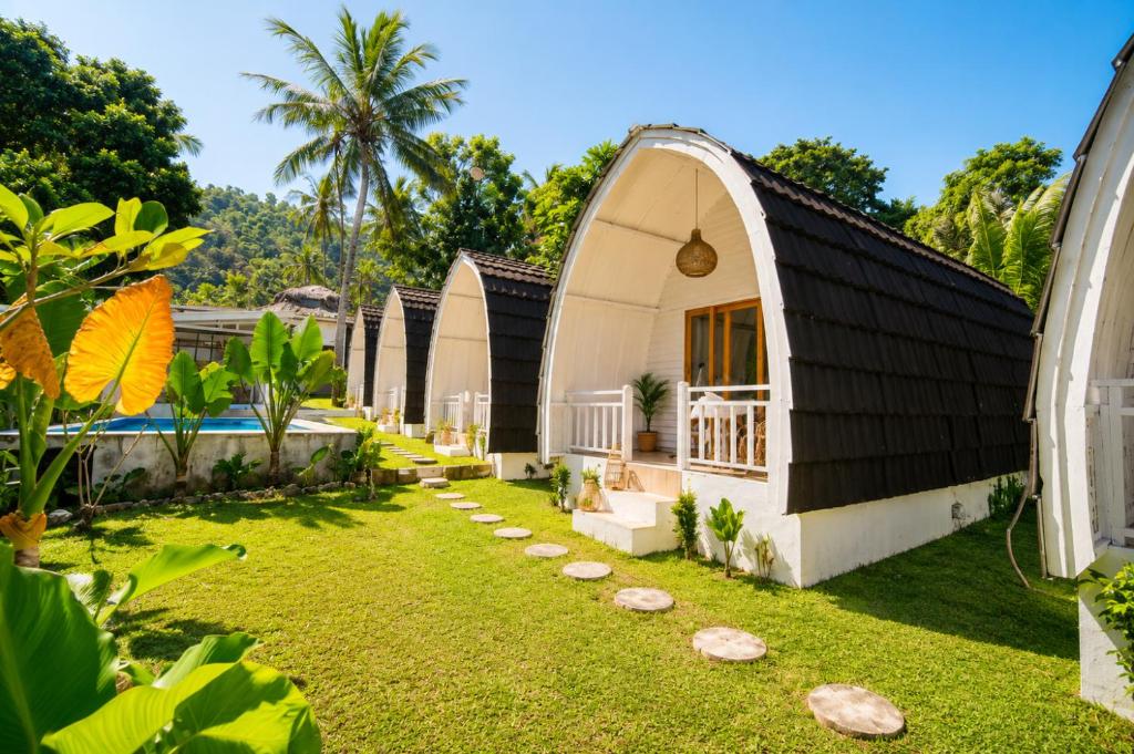 a house with a black roof and a yard at Kelapa Lodge - Lombok - in Senggigi