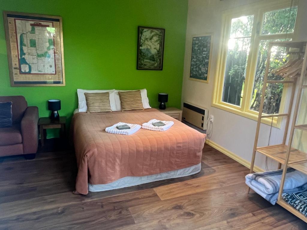 a green bedroom with a bed with two towels on it at Inner City Oasis in Invercargill