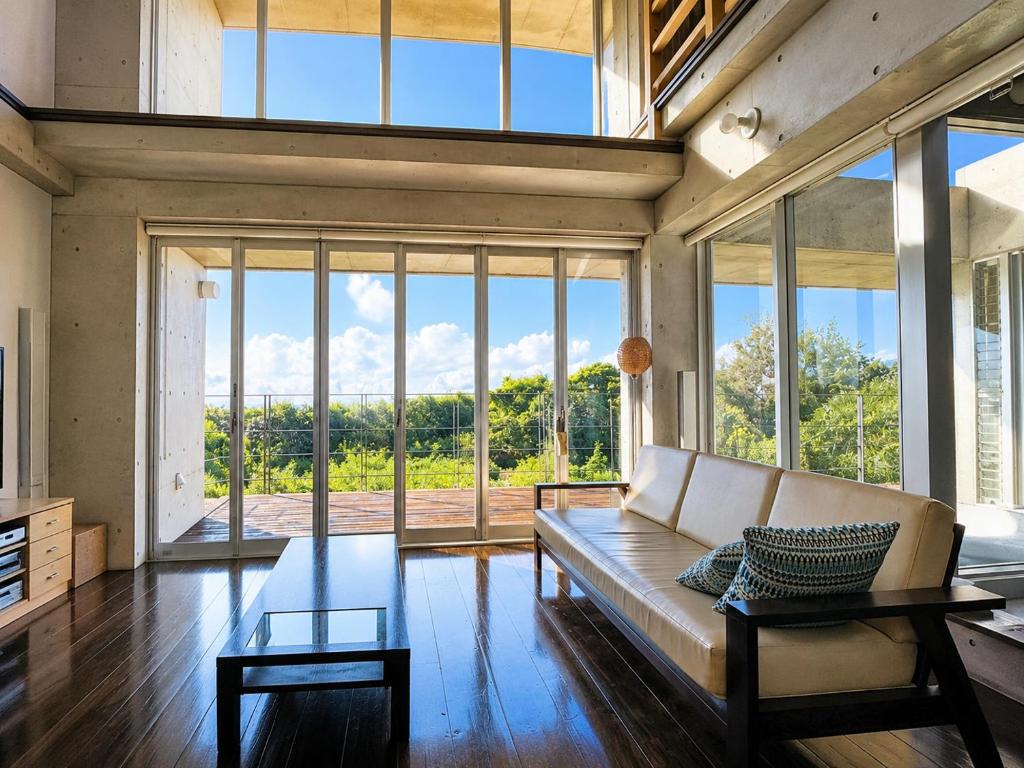 a living room with a couch and large windows at Private Villa The Beach AMAMI in Tatsugo
