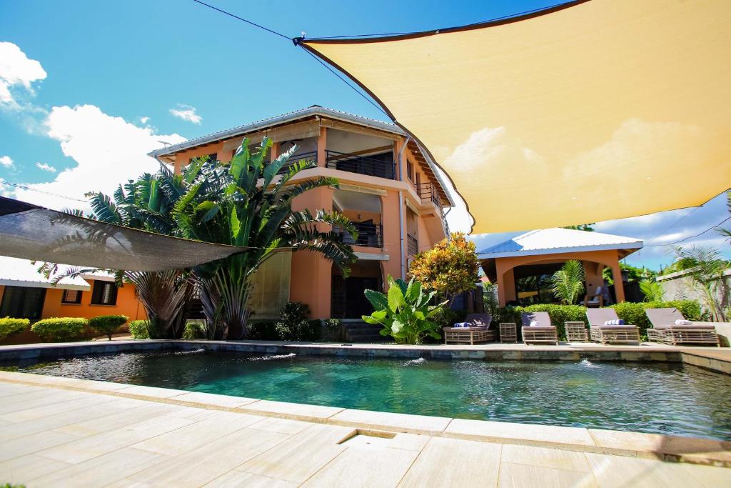 a house with a swimming pool in front of a house at Résidence Swiss Nosy be in Nosy Be
