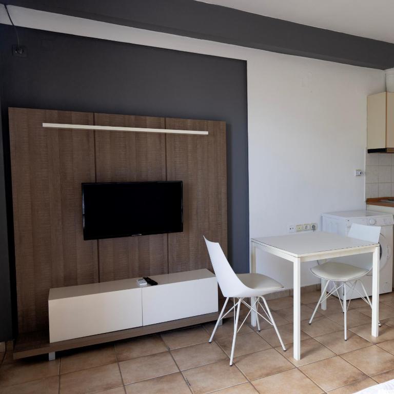 a living room with a table and a tv on a wall at Elia mini suite 2 in Larisa