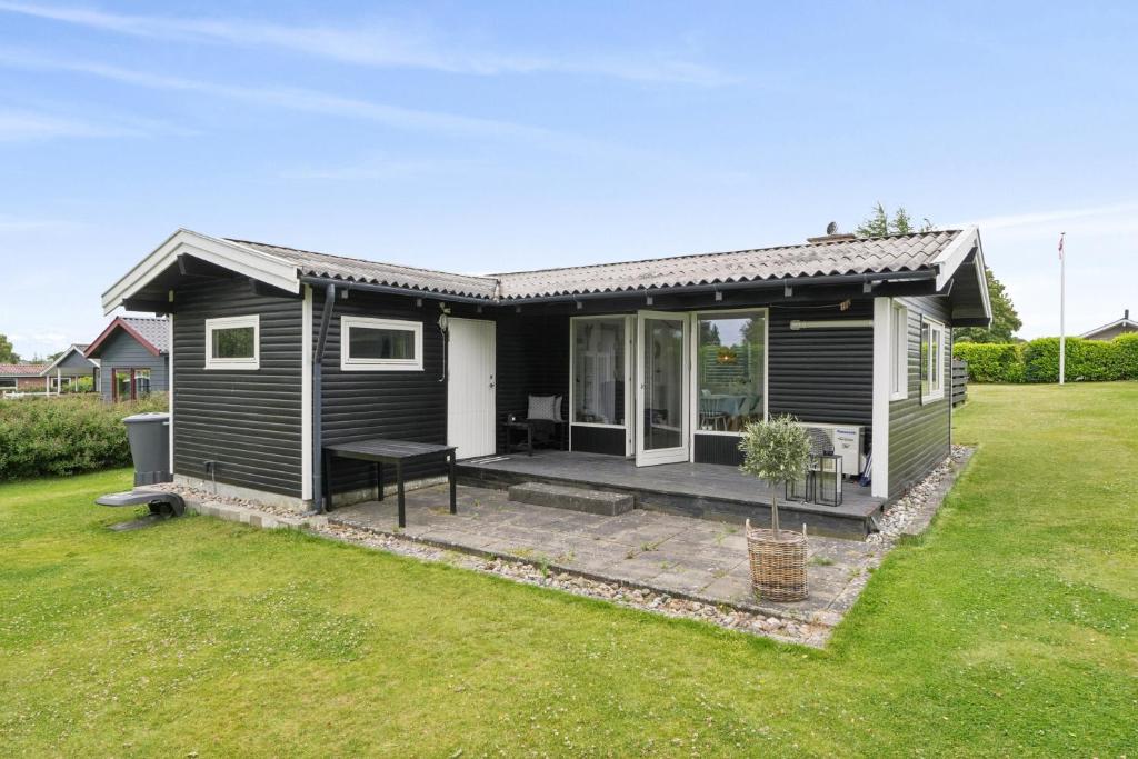 a black house with a patio in a yard at Nordic Style Summer House For Two in Bogense