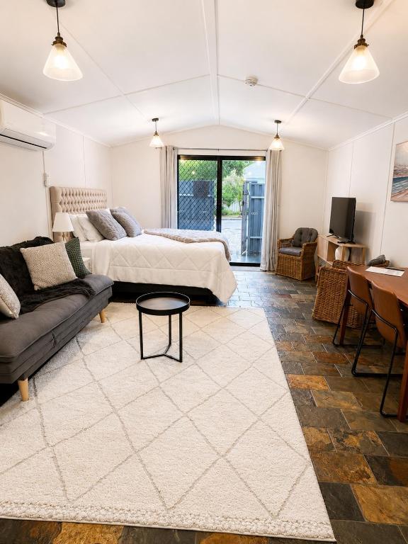 a bedroom with a bed and a couch and a table at Coastal Studio in Seacliff