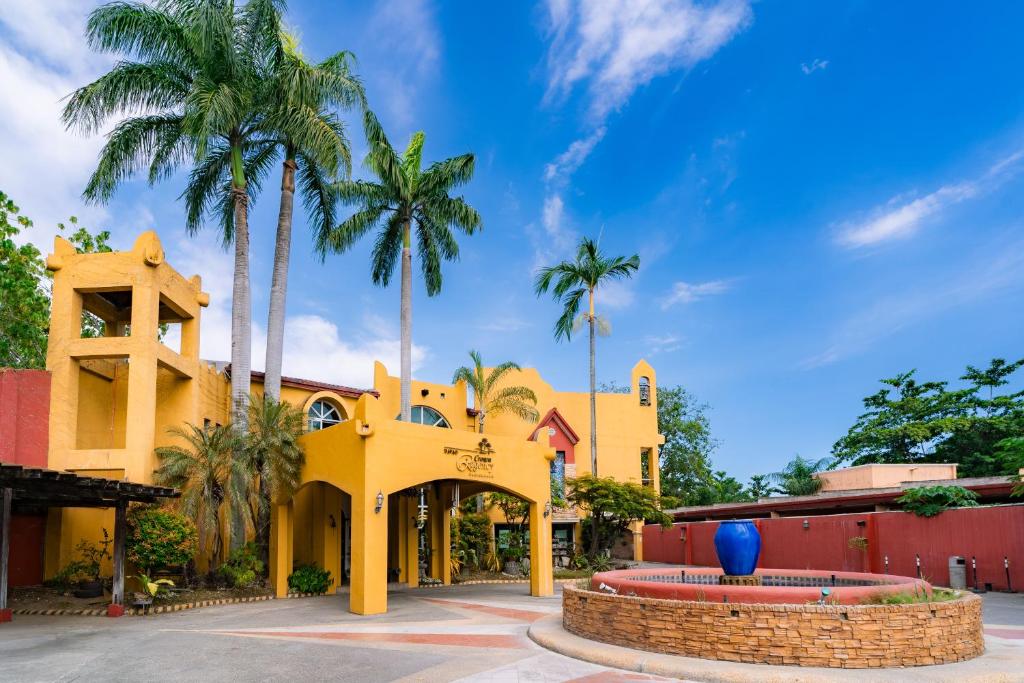 a yellow building with palm trees in front of it at Crown Regency Residences Davao in Davao City