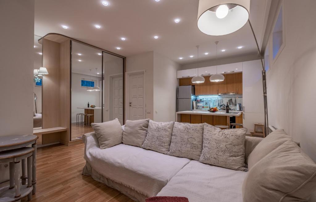 a living room with a white couch and a kitchen at Hyacinth House in Tbilisi City