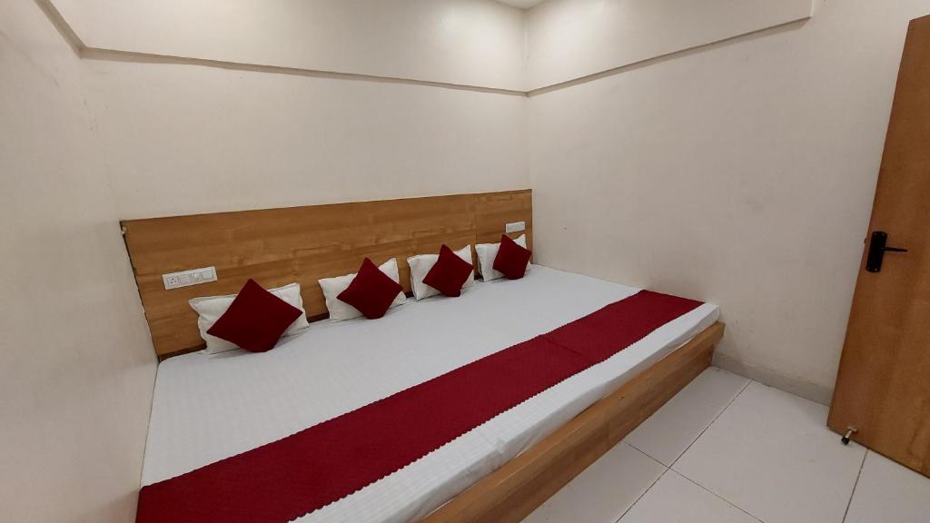 a bedroom with a bed with red and white pillows at Hotel Gokul in Ujjain