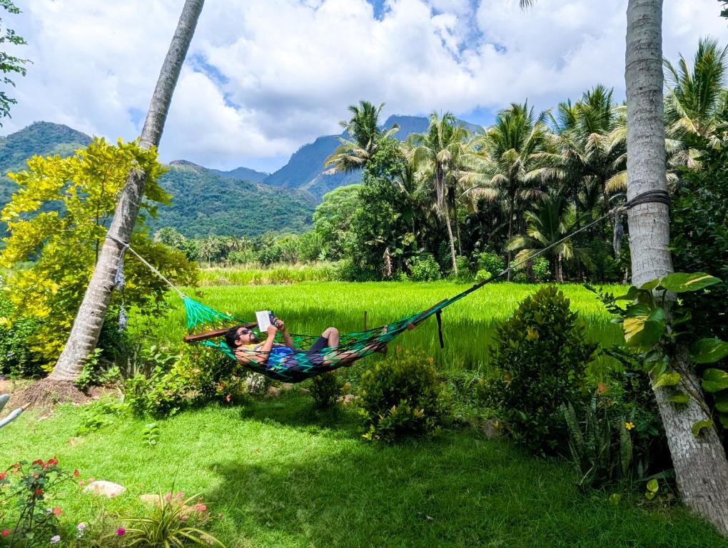 a woman laying in a hammock in a field at Crystal Water Inn in Bibile