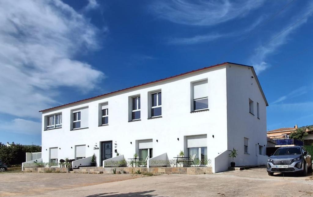 a white building with a car parked in front of it at Estación 87 Smart Workation y Relax Mediterráneo in Peniscola