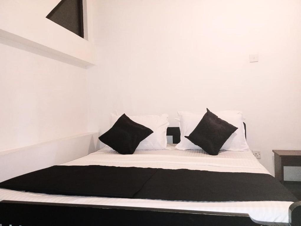 a bedroom with a bed with black and white pillows at Ceylander Suites in Kandy